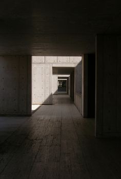 an empty hallway with light coming in from the end and shadows on the wall behind it