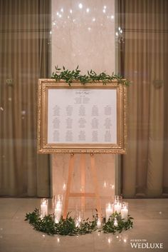 a wedding seating chart with candles and greenery