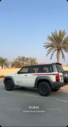 a white suv parked in a parking lot next to palm trees