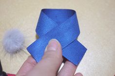 someone is making a paper origami bow with blue ribbon and pom - pom