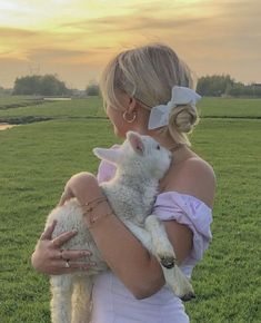 a woman is holding a lamb in a field