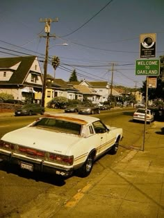 a white car parked on the side of a road next to a green street sign