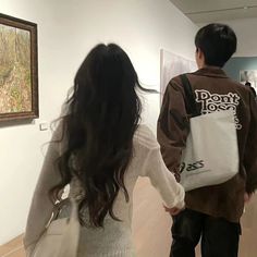 a man and woman are walking through an art gallery