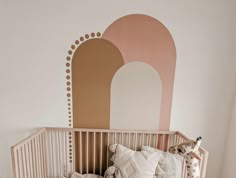 a baby's room with a crib, bedding and pillows on the floor