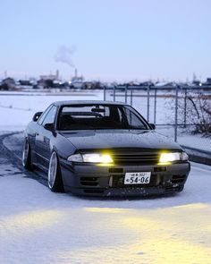 a car parked in the snow with its lights on