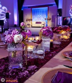 the table is set with purple flowers and candles