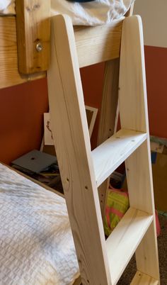 there is a ladder made out of wood on the floor in front of a bed