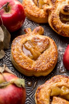 apple pies with caramel filling on a glass platter next to two red apples