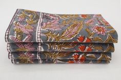 three folded napkins with floral designs on them