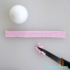 a pair of scissors and a ball on top of a piece of pink paper next to each other