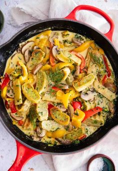 a skillet filled with mushrooms, peppers and other vegetables on top of a table