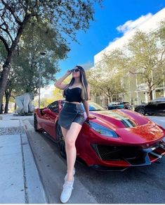 a woman leaning on the hood of a red sports car