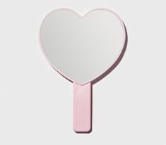 a pink heart shaped mirror sitting on top of a table