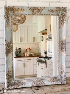 a mirror that is on the side of a brick wall in a kitchen with white cabinets