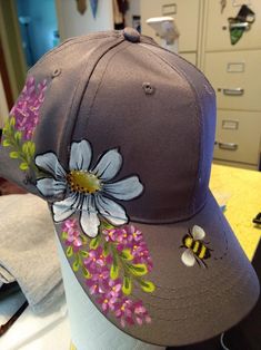 a hat with flowers and bees on it sitting on top of a mannequin