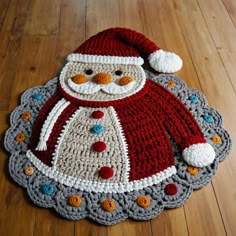 a crocheted santa clause is sitting on the floor next to a wooden floor