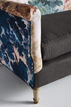 an upholstered couch with blue and white paint splattered on the back