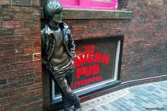 a statue of a woman standing next to a brick building with a sign on it