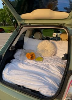 the trunk of a car with a bed and pillows in it