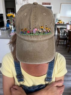 a woman wearing a hat with flowers embroidered on the front and back of her head