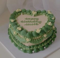 a heart shaped cake with green frosting and flowers