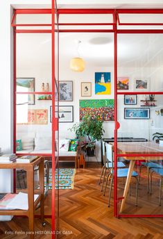 an open room with red glass partitions and wooden flooring, along with pictures on the wall