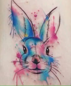 a colorful rabbit tattoo on the right side of the leg, with watercolor splashs all over it