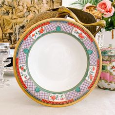 an ornately decorated plate sits on a table next to other plates and vases