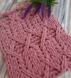 a pink blanket sitting on top of a wooden floor next to a potted plant