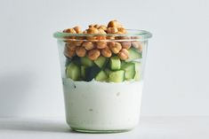 a glass jar filled with cucumbers and nuts on top of a white surface