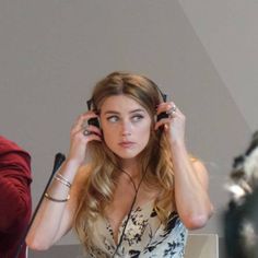 a woman sitting at a table with headphones in her ears and looking off to the side