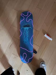 a person standing next to a blue skateboard on a wooden floor with neon lights