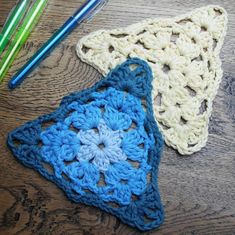 two crocheted doilies sitting on top of a wooden table next to colored pencils