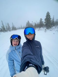 two people standing in the snow with skis on and one person holding out their hand