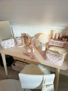 a wooden table topped with lots of cosmetics and personal care items next to a white chair