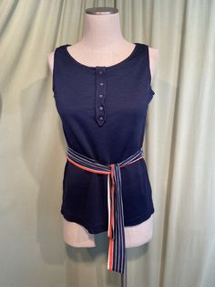 This is a sweet, vintage top from the 70s. Label reads, Trissi. Tagged a size medium. The bust measures 36" without stretching, see measurements below.   Made of navy blue acetate.  The top has a wide round neckline & a faux button placket with 5 decorative buttons. It is sleeveless & hip length. It has string belt loops & a striped belt of orange, white & blue. There are vents on the side seams at the hemline. The top is in good condition!  No damage or wear.  No soil or stains.  Classic!  Measurements were taken with the garment lying flat. If you have never worn vintage before, please measure yourself!! Vintage sizes run smaller than today's sizes, know your measurements before buying! Bust measured from side seam to side seam at the underarm: 18" unstretched for a 36" or slightly small Retro Navy Tops For Summer, Navy Retro Summer Tops, Retro Tank Vest, Retro Fitted Sleeveless Tank Top, Retro Fitted Tank Top, Fitted Retro Sleeveless Tank Top, Retro Sleeveless Cotton Tops, Retro Cotton Vest-style Top, Fitted Navy Tank Top For Spring