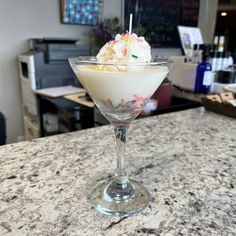 an ice cream sundae with sprinkles in a glass on a counter