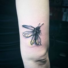 a black and yellow insect tattoo on the arm