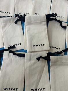 many bags with black writing on them sitting on a blue cloth covered tablecloth that says, what?