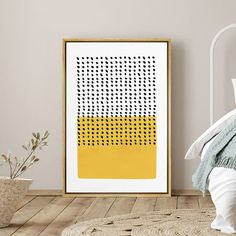 a white bed sitting next to a yellow and black art print on a wooden floor