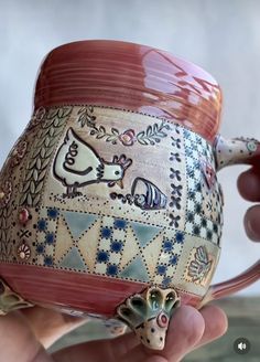 a hand holding a ceramic mug with an animal decoration on the outside and inside it