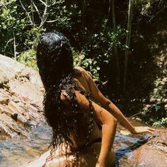 a naked woman sitting on top of a rock in the water