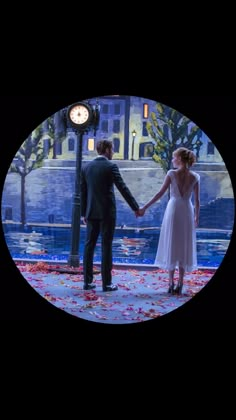 a man and woman holding hands in front of a city street light with flowers on the ground