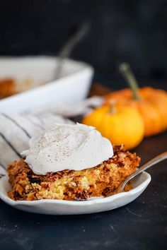 a close up of a plate of food with whipped cream on top and pumpkins in the background