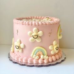 a pink cake decorated with flowers and rainbows