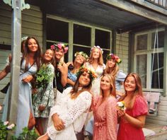 a group of women standing next to each other in front of a house