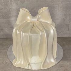 a white cake with a large bow on it's top sitting on a plate