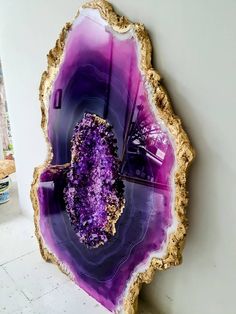 a piece of wood with purple and gold decorations on it's sides, hanging from the wall