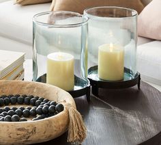 two candles are sitting on a table next to some rocks and a bowl with beads