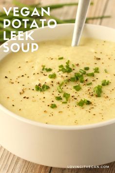 a white bowl filled with soup on top of a wooden table next to green beans